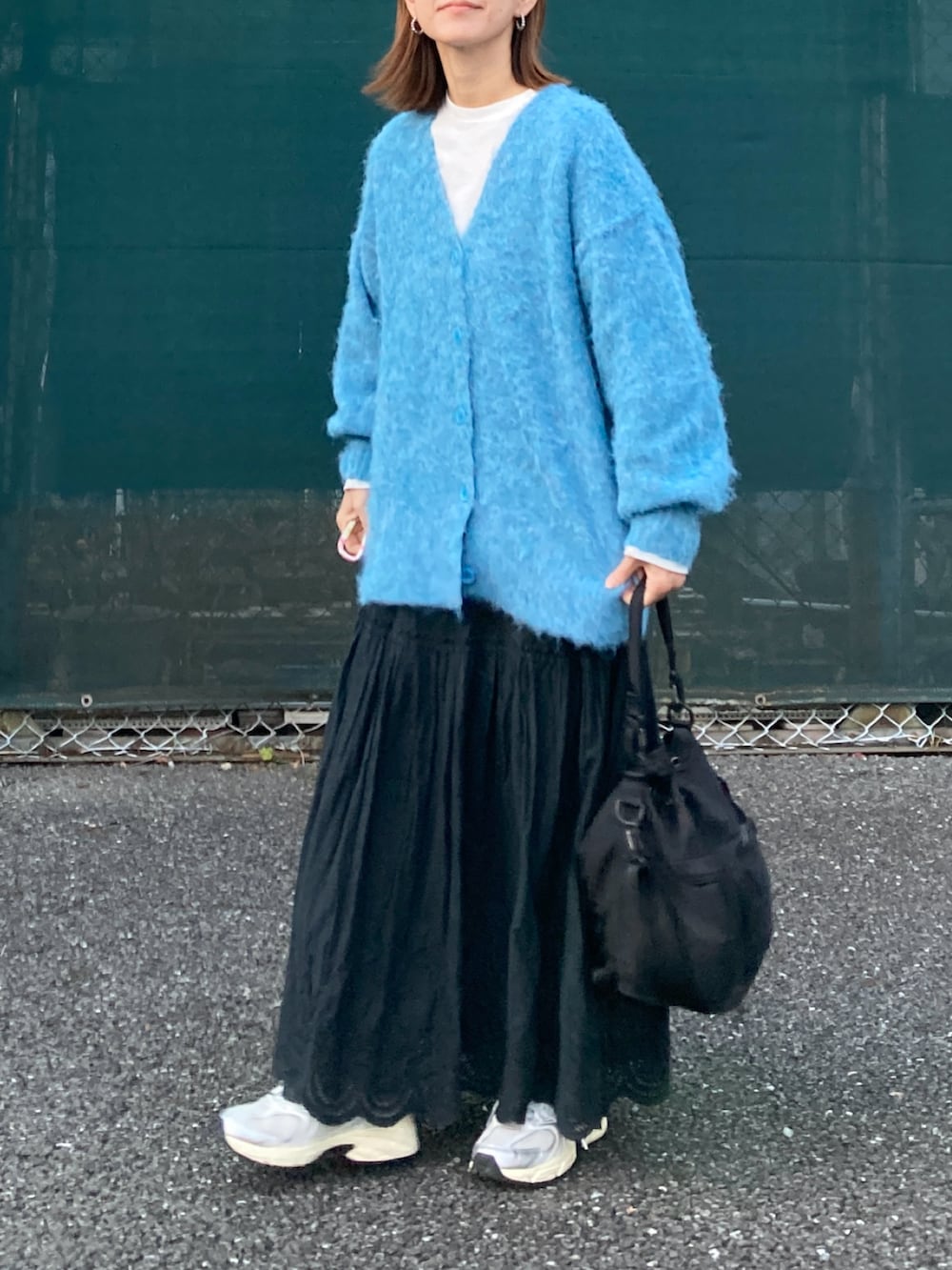 ブルー系のカーディガン/ボレロ、ブラック系のスカート、ブラック系のショルダーバッグを着用したレディースの冬コーディネートの2枚目の写真