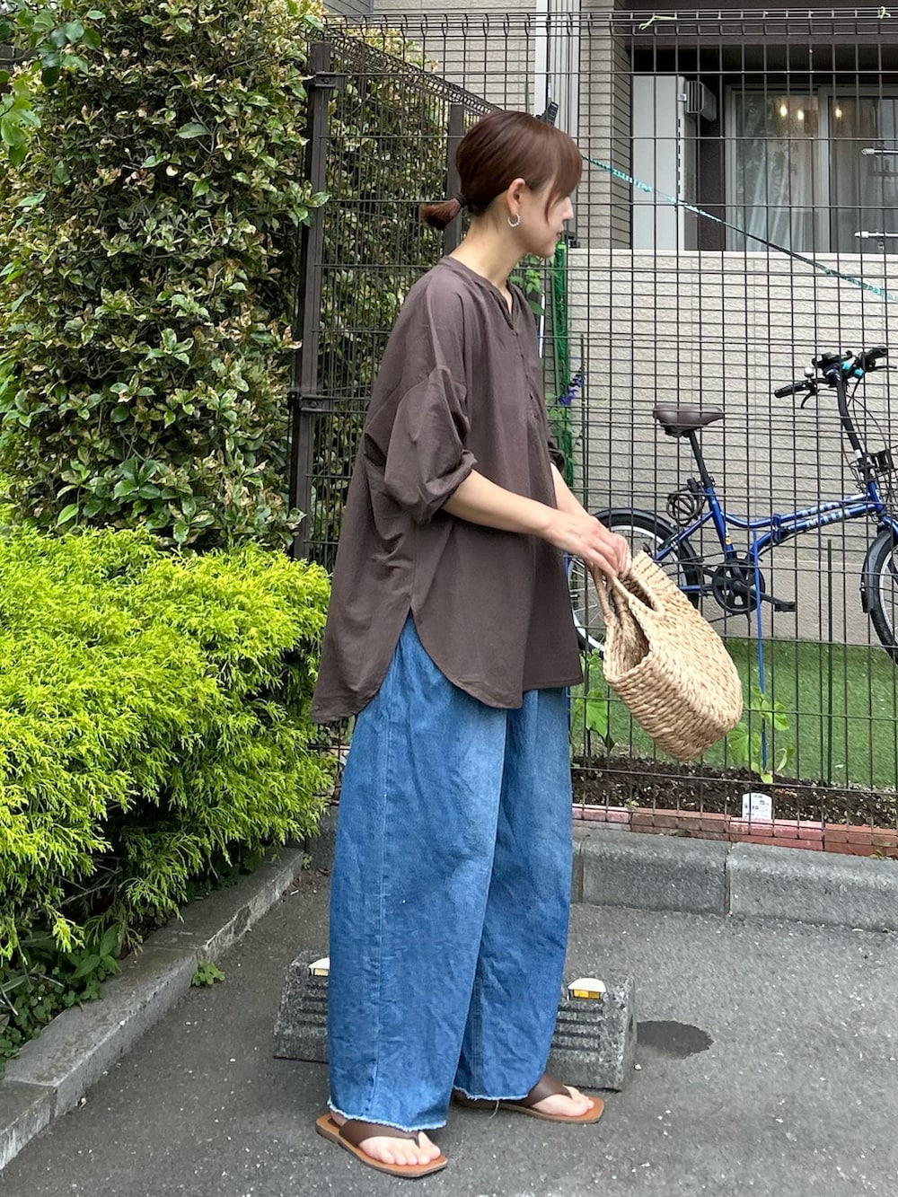 ブラウン系のTシャツ/カットソー、ブルー系のデニムパンツ、ベージュ系のかごバッグを着用したレディースの春コーディネートの2枚目の写真