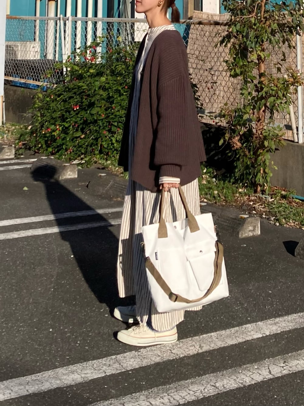 ブラウン系のカーディガン/ボレロ、ホワイト系のトートバッグ、ホワイト系のワンピースを着用したレディースの秋コーディネートの5枚目の写真