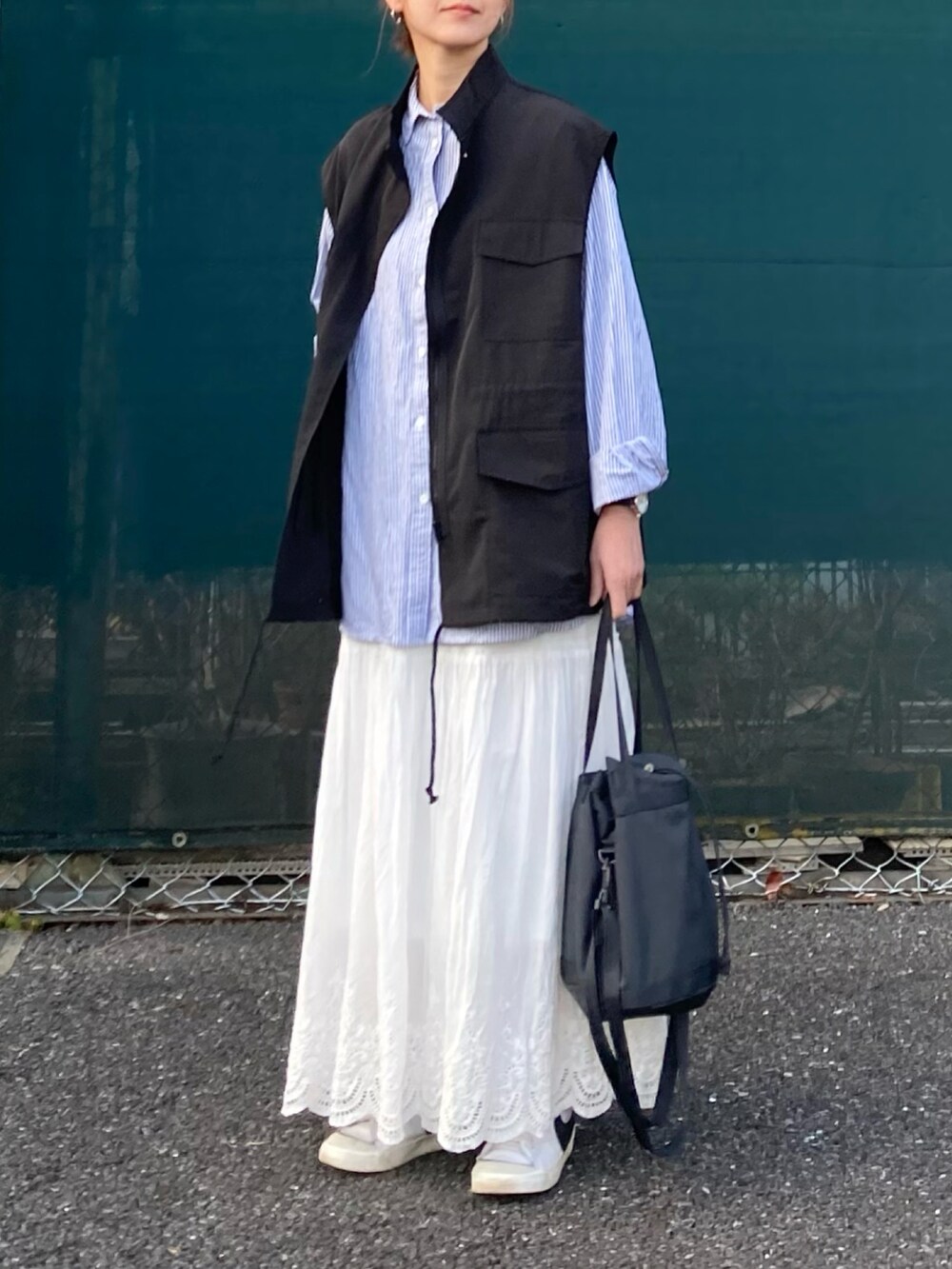 ブラック系のベスト、ブルー系のシャツ/ブラウス、ホワイト系のスカートを着用したレディースの冬コーディネートの2枚目の写真