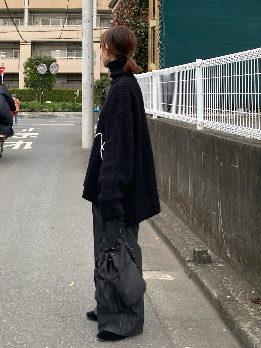 ブラック系のニット/セーター、グレー系のパンツ、ブラック系のショルダーバッグを着用したレディースの冬コーディネートの4枚目の写真