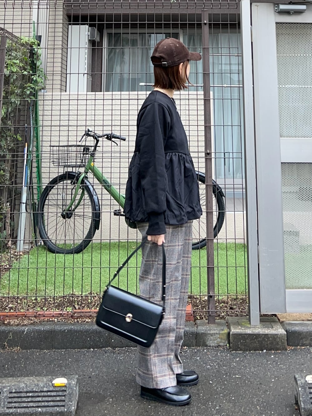 ブラック系のスウェット、ブラック系のハンドバッグ、ブラウン系のキャップを着用したレディースの秋コーディネートの4枚目の写真