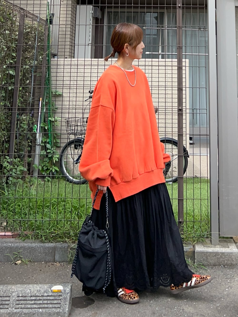 オレンジ系のスウェット、ブラック系のトートバッグ、ブラック系のスカートを着用したレディースの春コーディネートの3枚目の写真