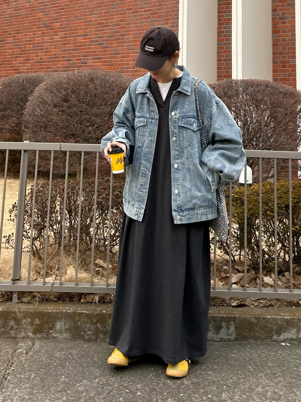 ブルー系のデニムジャケット、グレー系のワンピース、イエロー系のスニーカーを着用したレディースの冬コーディネートの5枚目の写真