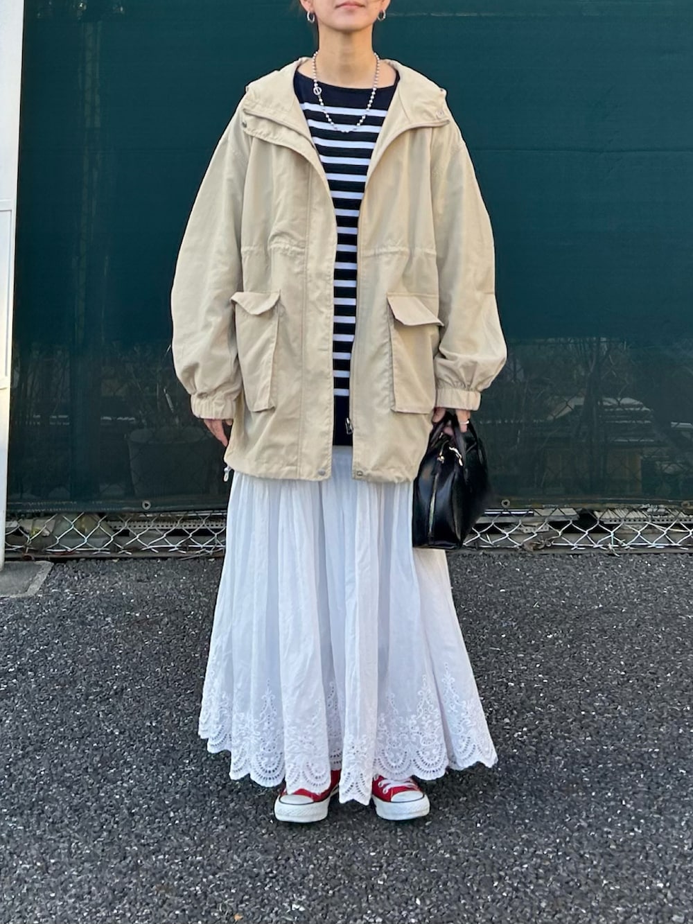 ベージュ系のマウンテンパーカー、ブルー系のTシャツ/カットソー、ホワイト系のスカートを着用したレディースの春コーディネートの2枚目の写真