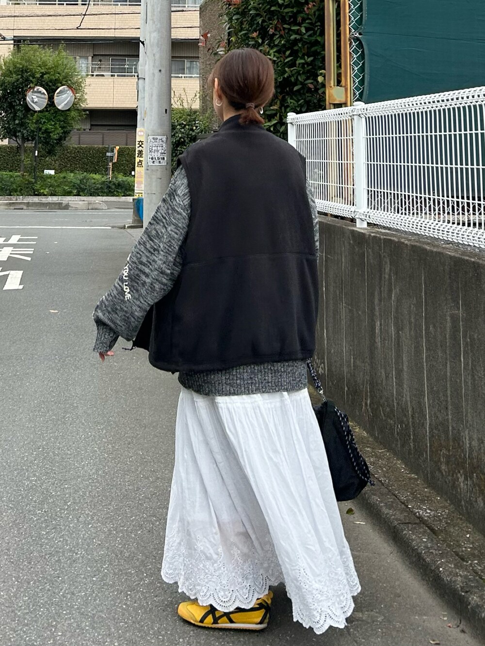 ブラック系のベスト、グレー系のニット/セーター、ブラック系のトートバッグを着用したレディースの秋コーディネートの4枚目の写真