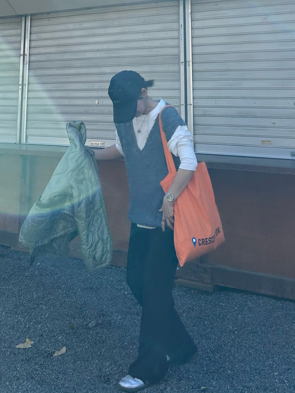 グリーン系のノーカラージャケット、グレー系のベスト、オレンジ系のトートバッグを着用したレディースの冬コーディネートの5枚目の写真