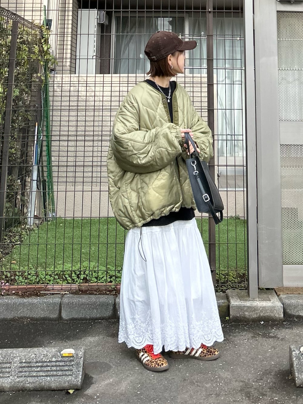 ブラック系のスウェット、ホワイト系のスカート、グリーン系のブルゾンを着用したレディースの冬コーディネートの3枚目の写真