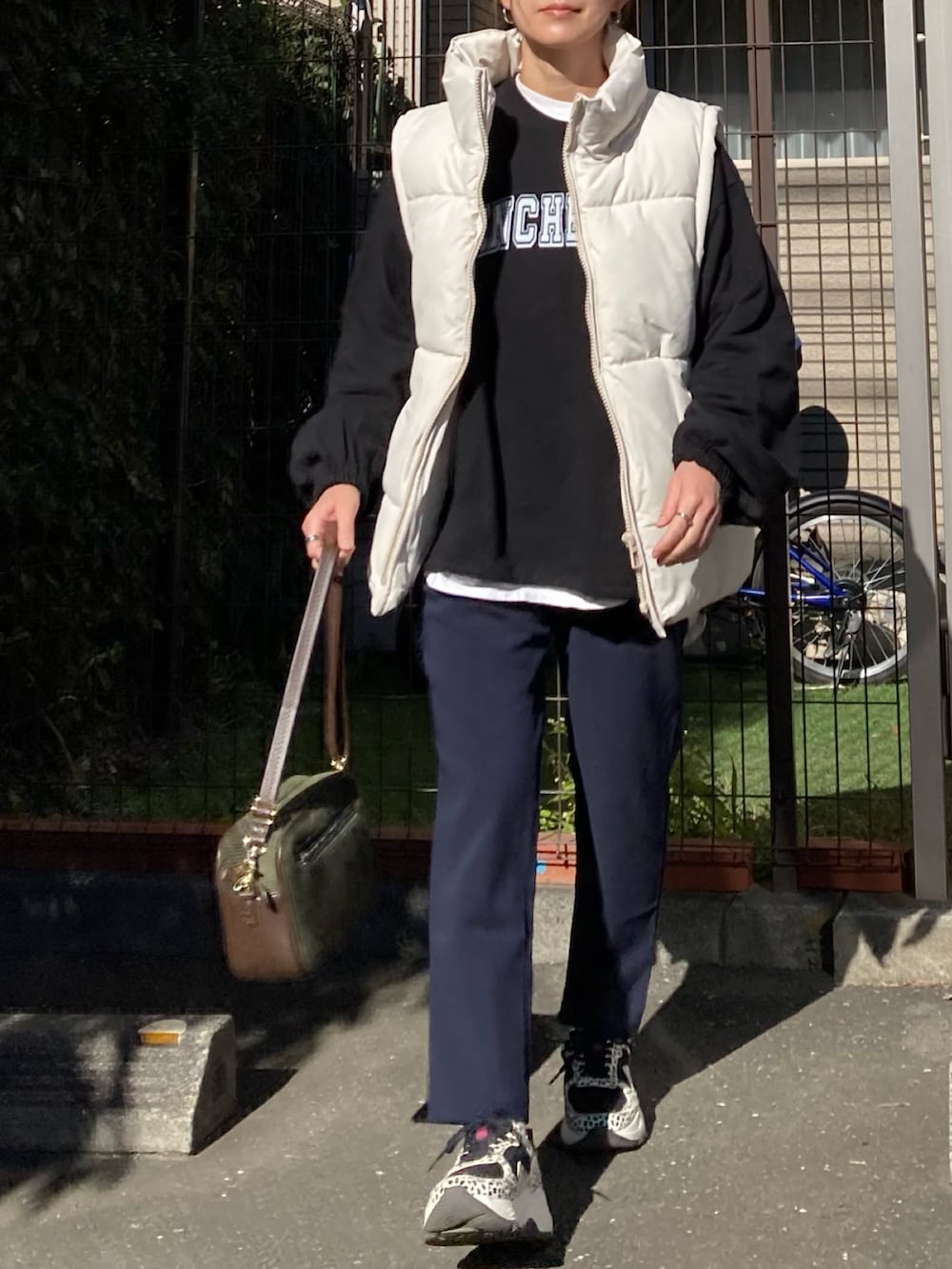 ベージュ系のダウンベスト、ブラック系のその他トップス、グリーン系のショルダーバッグを着用したレディースの冬コーディネートの3枚目の写真