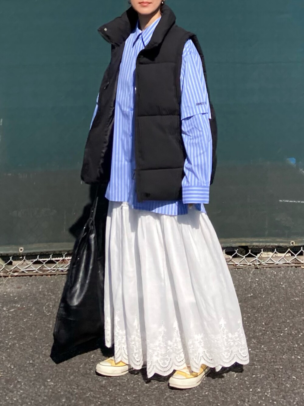 ブラック系のダウンベスト、ブルー系のシャツ/ブラウス、ブラック系のトートバッグを着用したレディースの冬コーディネートの2枚目の写真