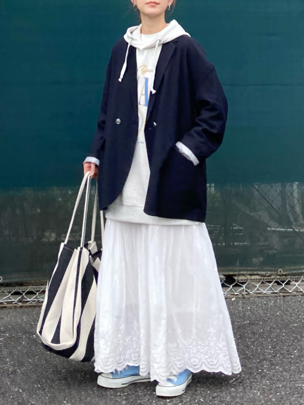 ベージュ系のパーカー、ホワイト系のスカート、ブラック系のトートバッグを着用したレディースの春コーディネートの3枚目の写真