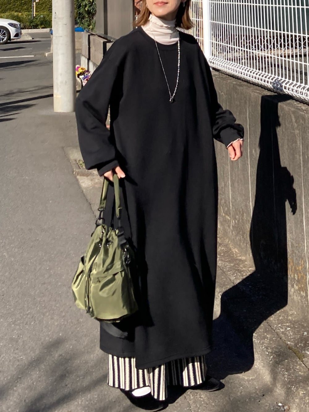 ブラック系のワンピース、ブラック系のその他パンツ、グリーン系のショルダーバッグを着用したレディースの冬コーディネートの3枚目の写真