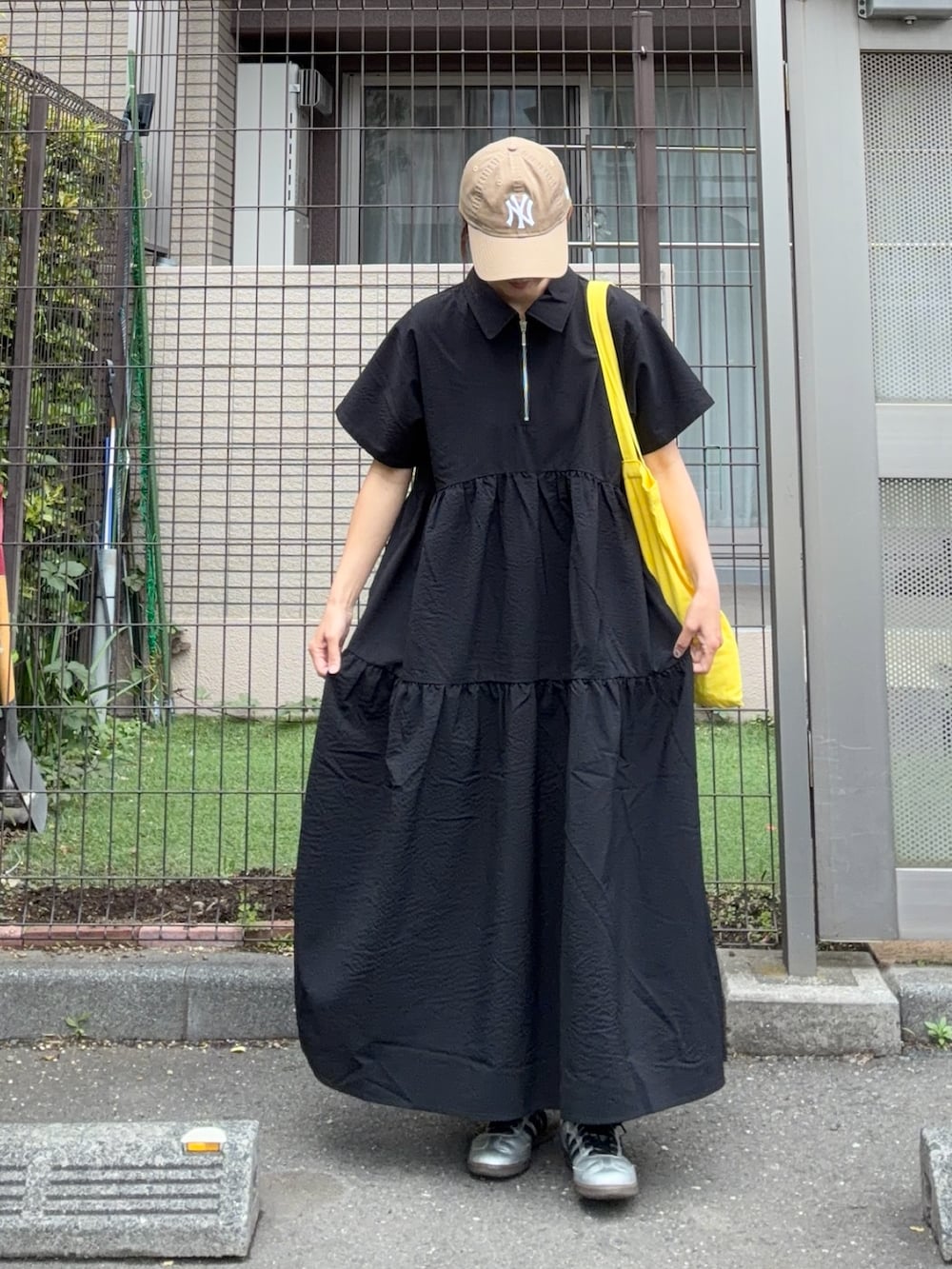 ブラック系のワンピース、イエロー系のトートバッグ、ベージュ系のキャップを着用したレディースの春コーディネートの5枚目の写真
