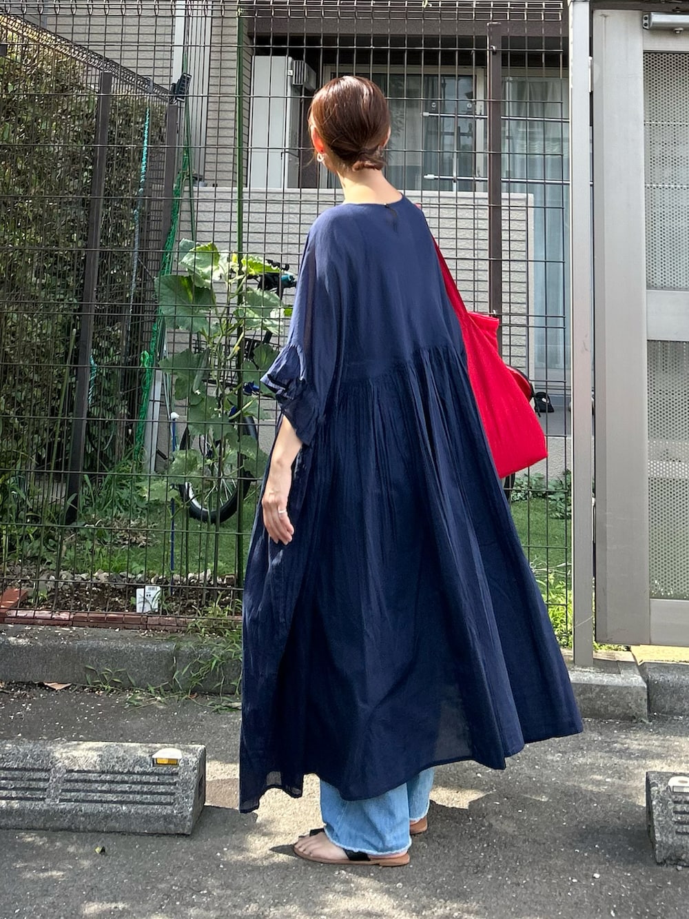 ブルー系のデニムパンツ、ブルー系のワンピース、レッド系のトートバッグを着用したレディースの夏コーディネートの2枚目の写真