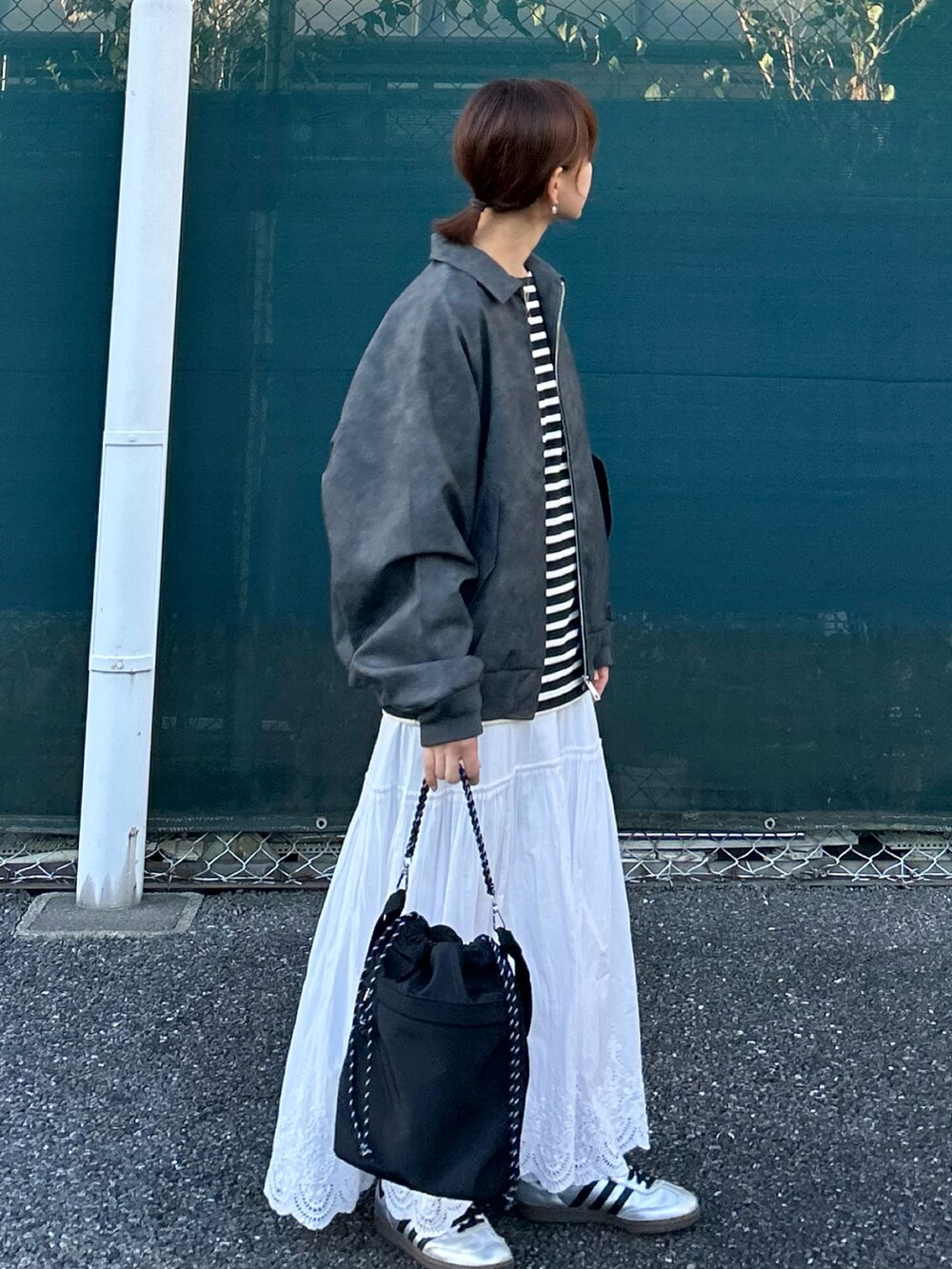 ブラック系のブルゾン、ブラック系のトートバッグ、ホワイト系のスカートを着用したレディースの秋コーディネートの5枚目の写真