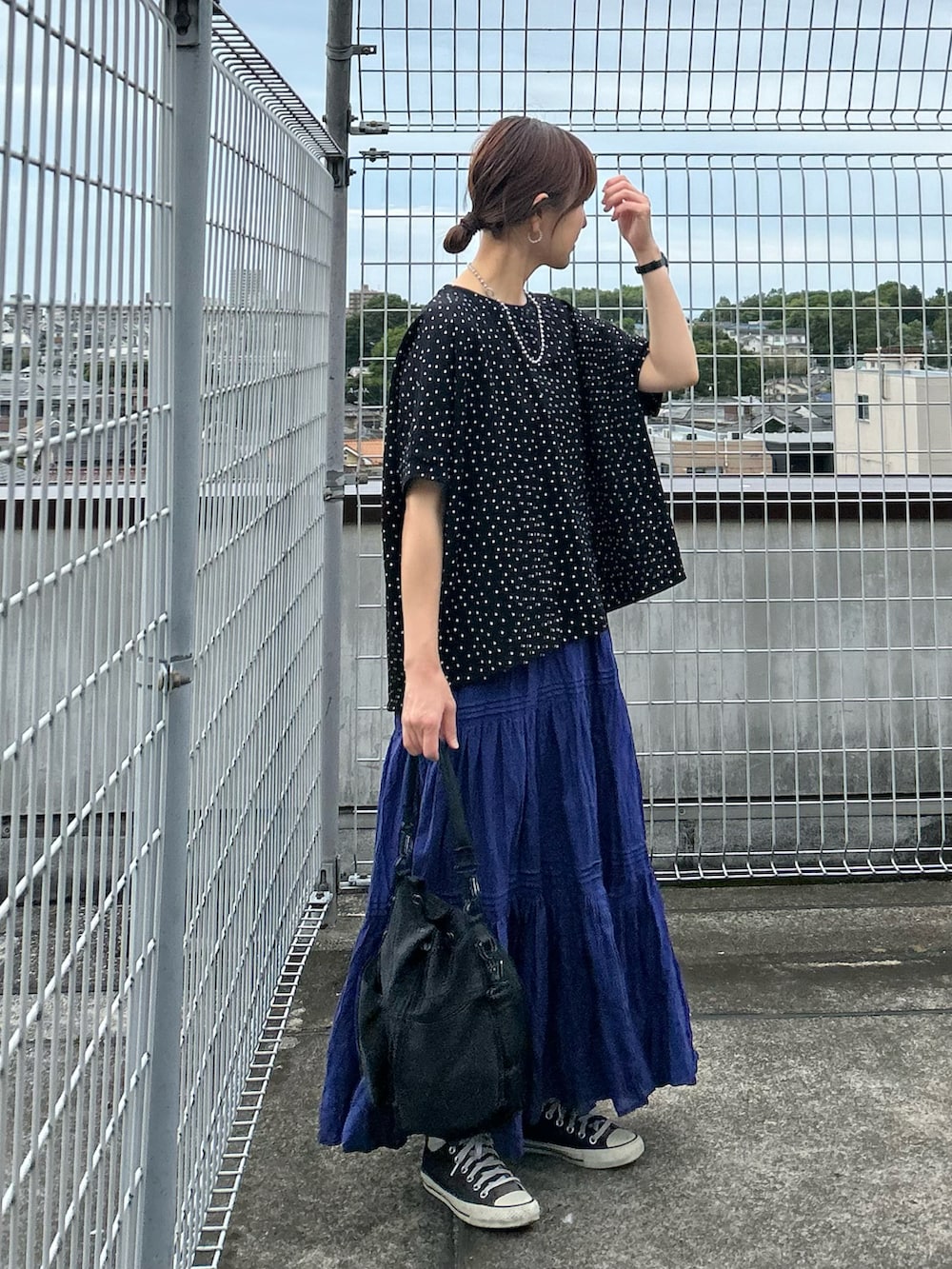 ブラック系のTシャツ/カットソー、ブルー系のスカート、ブラック系のショルダーバッグを着用したレディースの春コーディネートの2枚目の写真