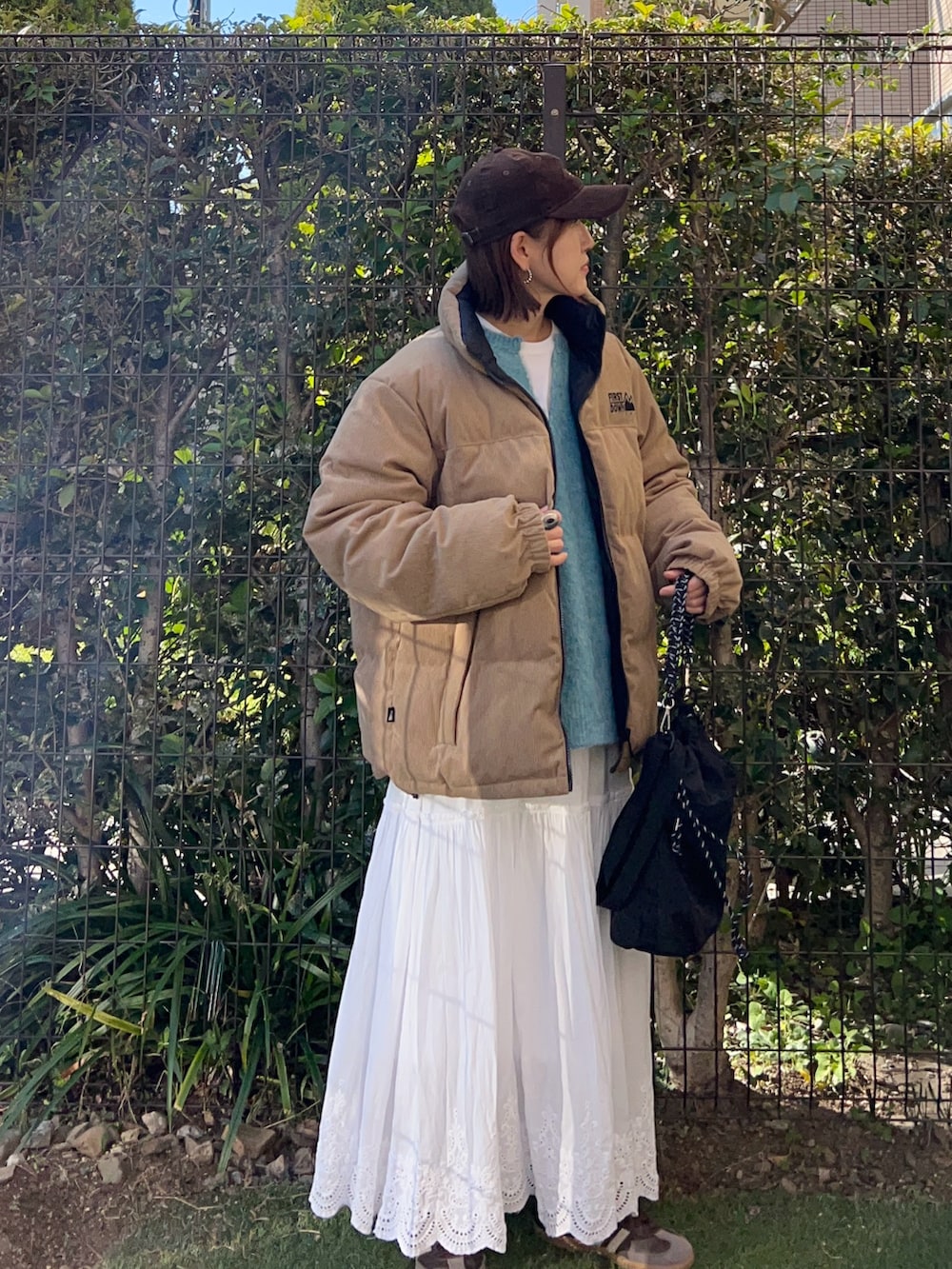 ブルー系のニット/セーター、ベージュ系のダウンジャケット/コート、ホワイト系のスカートを着用したレディースの冬コーディネートの2枚目の写真