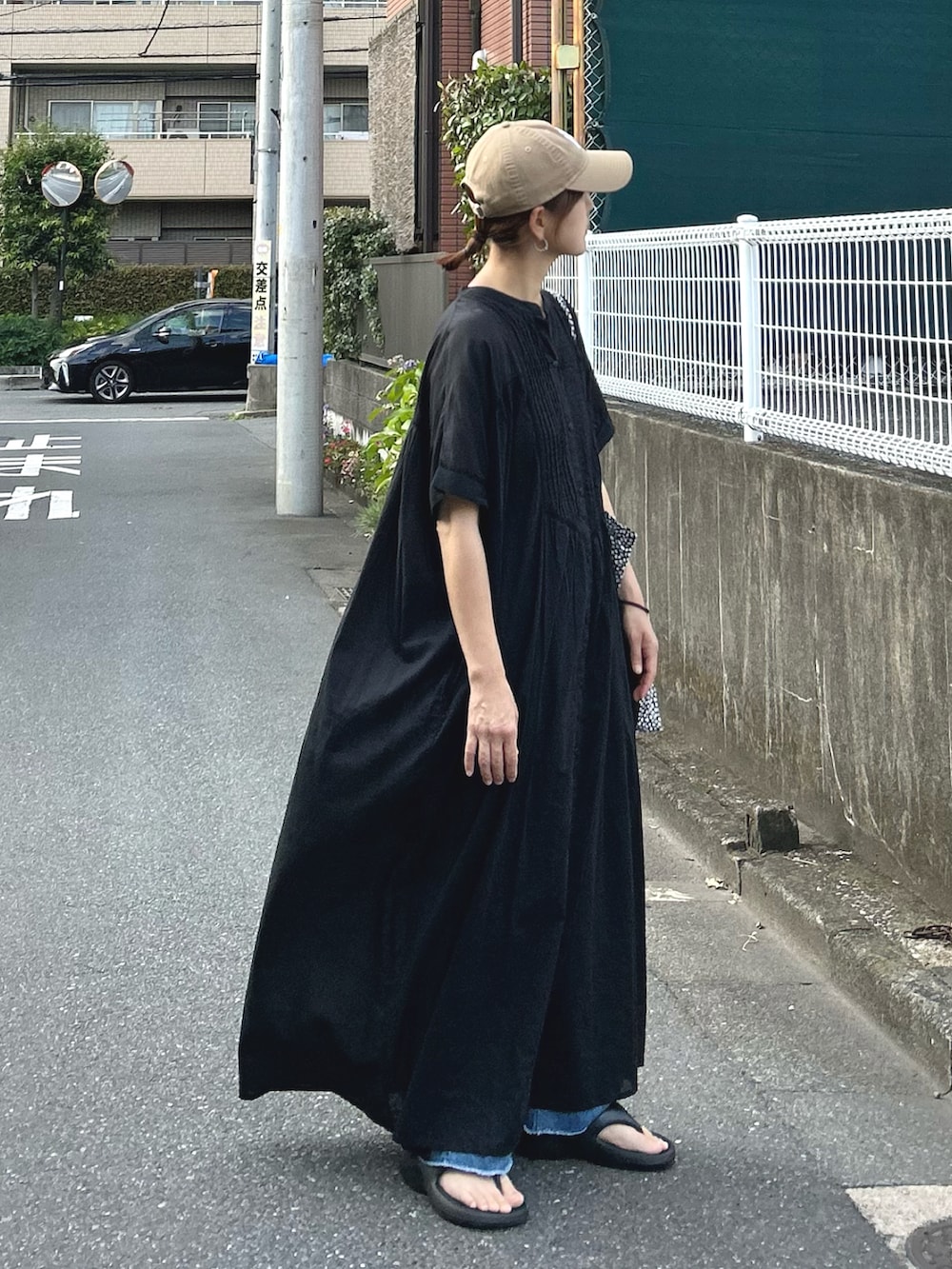 ブルー系のデニムパンツ、ブラック系のワンピース、ベージュ系のキャップを着用したレディースの夏コーディネートの4枚目の写真