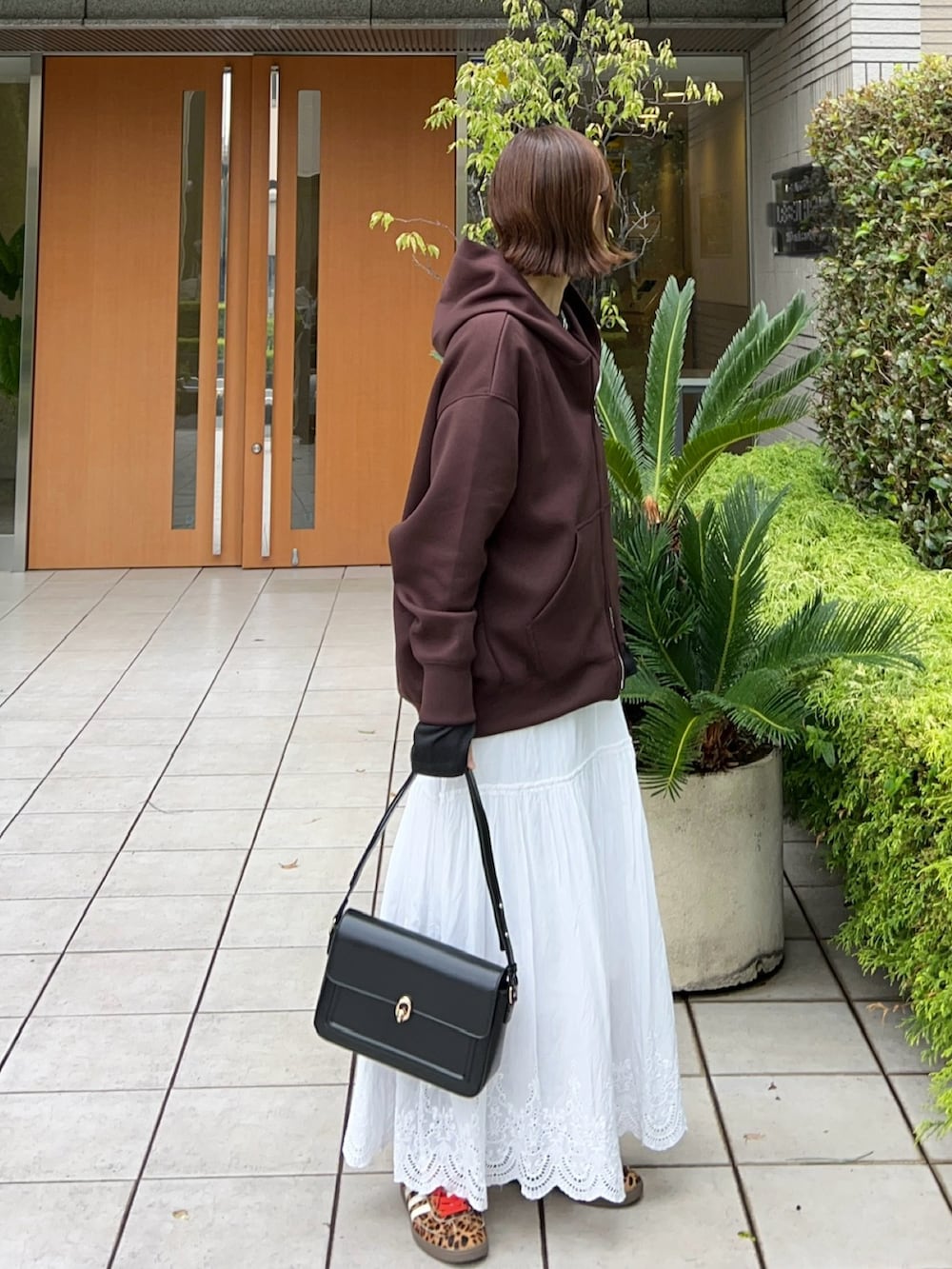 ブラウン系のパーカー、ブラック系のTシャツ/カットソー、ホワイト系のスカートを着用したレディースの秋コーディネートの2枚目の写真