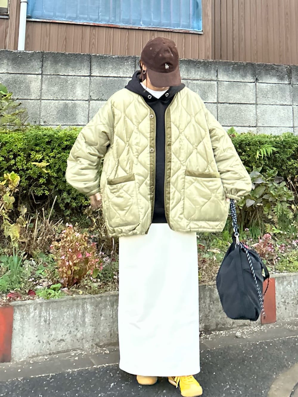 ブラック系のパーカー、ホワイト系のスカート、ブラック系のトートバッグを着用したレディースの冬コーディネートの3枚目の写真