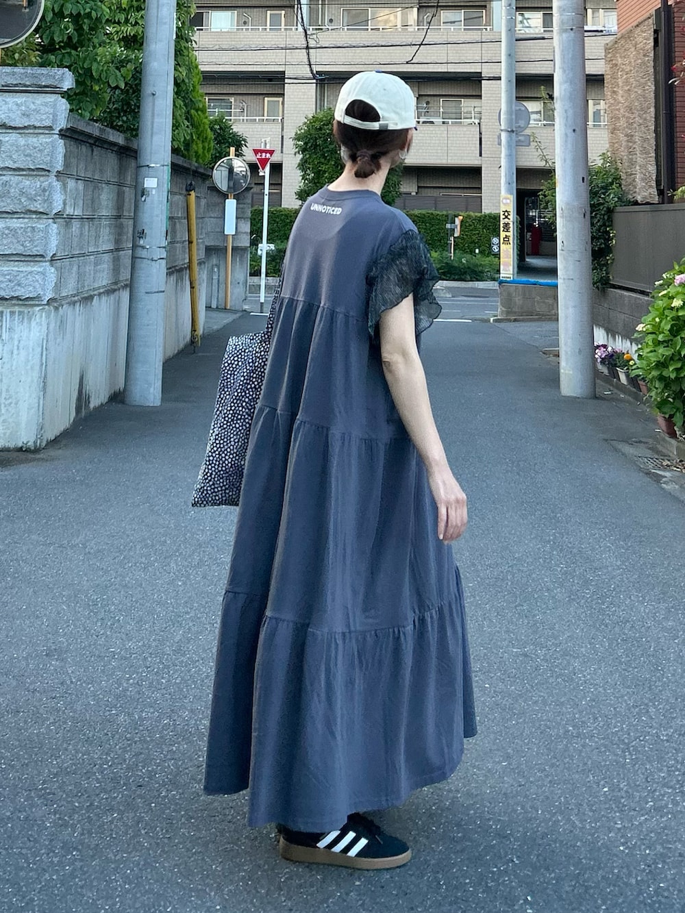 ブラック系のワンピース、ブラック系のトートバッグ、ブルー系のキャップを着用したレディースの夏コーディネートの3枚目の写真