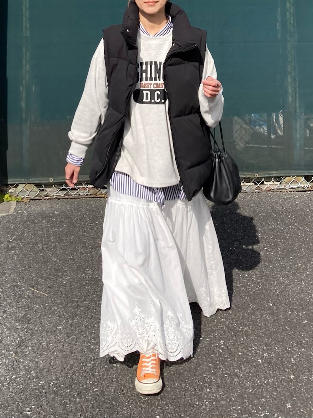 ブラック系のダウンベスト、ベージュ系のスウェット、ホワイト系のスカートを着用したレディースの冬コーディネートの3枚目の写真