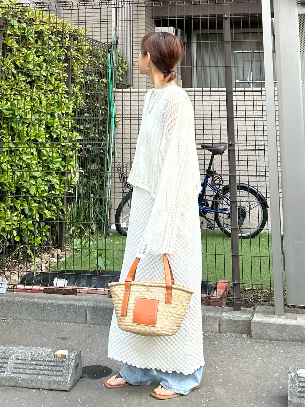 ホワイト系のワンピース、ブラウン系のかごバッグ、ブルー系のデニムパンツを着用したレディースの春コーディネートの3枚目の写真