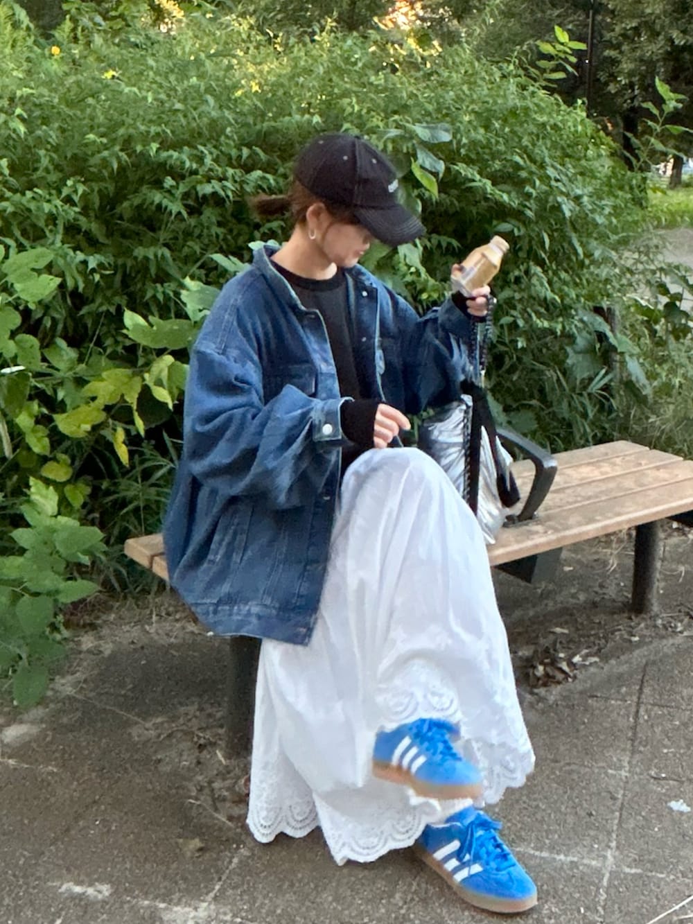 ホワイト系のスカート、ブルー系のデニムジャケット、ブラック系のスウェットを着用したレディースの秋コーディネートの2枚目の写真