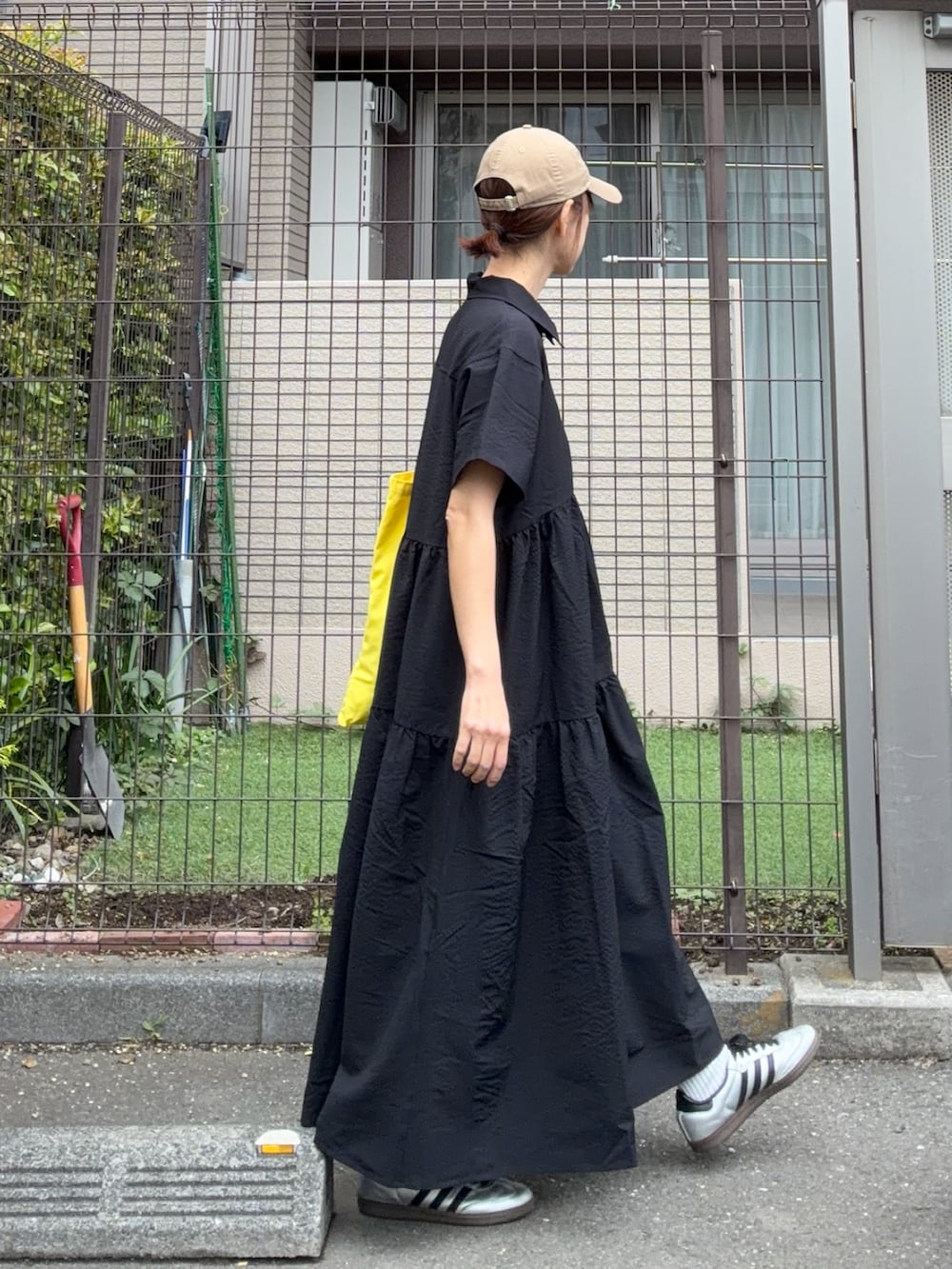 ブラック系のワンピース、イエロー系のトートバッグ、ベージュ系のキャップを着用したレディースの春コーディネートの2枚目の写真