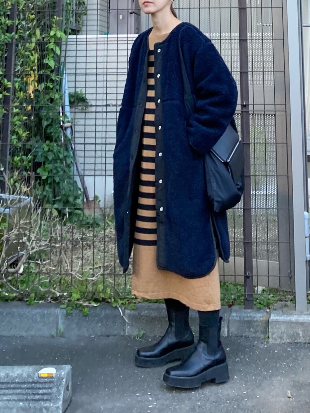 ブルー系のノーカラージャケット、ブラック系のハンドバッグ、ブラウン系のワンピースを着用したレディースの冬コーディネートの3枚目の写真