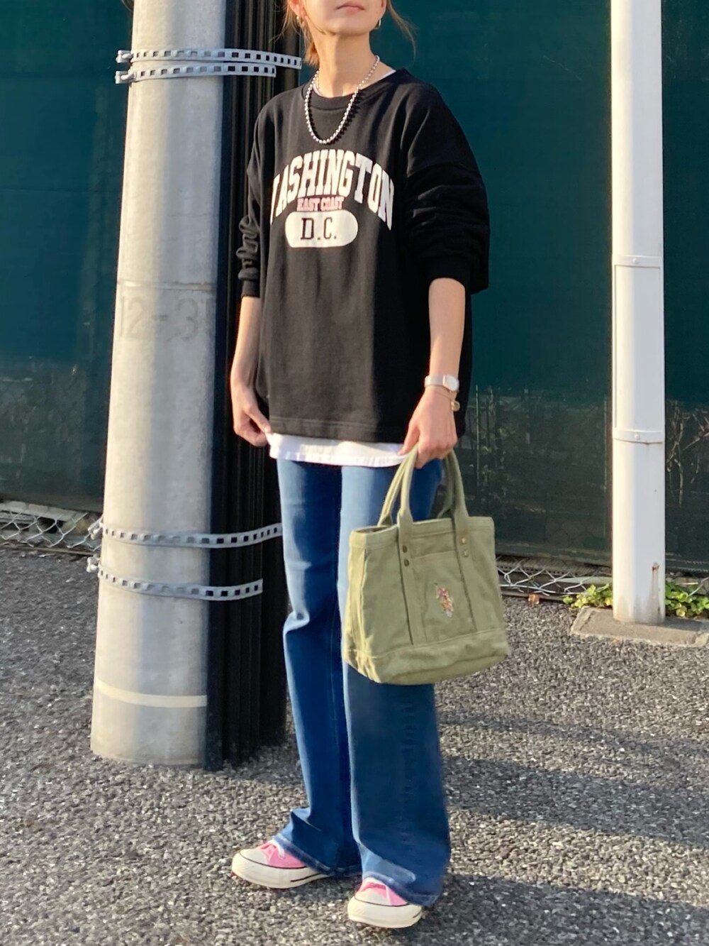 ブラック系のスウェット、ブルー系のデニムパンツ、グリーン系のトートバッグを着用したレディースの春コーディネートの4枚目の写真