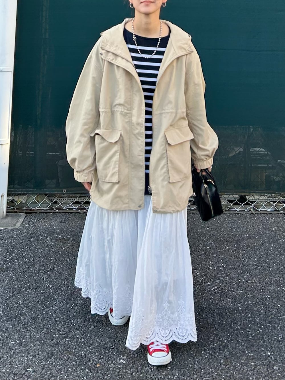 ベージュ系のマウンテンパーカー、ブルー系のTシャツ/カットソー、ホワイト系のスカートを着用したレディースの春コーディネートの3枚目の写真