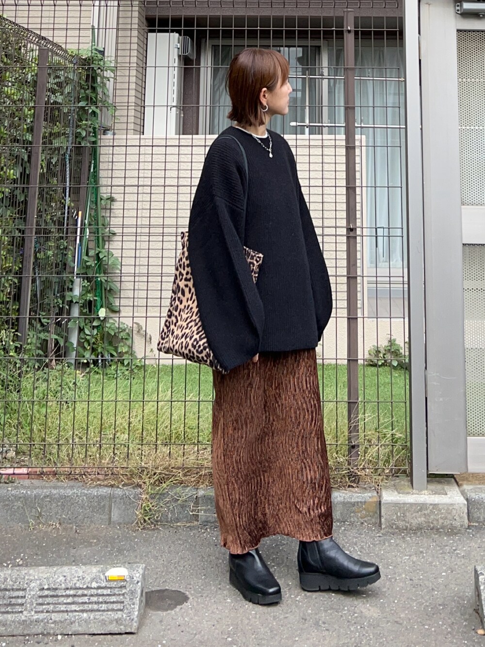 ブラウン系のスカート、ブラウン系のトートバッグ、ブラック系のニット/セーターを着用したレディースの秋コーディネートの3枚目の写真