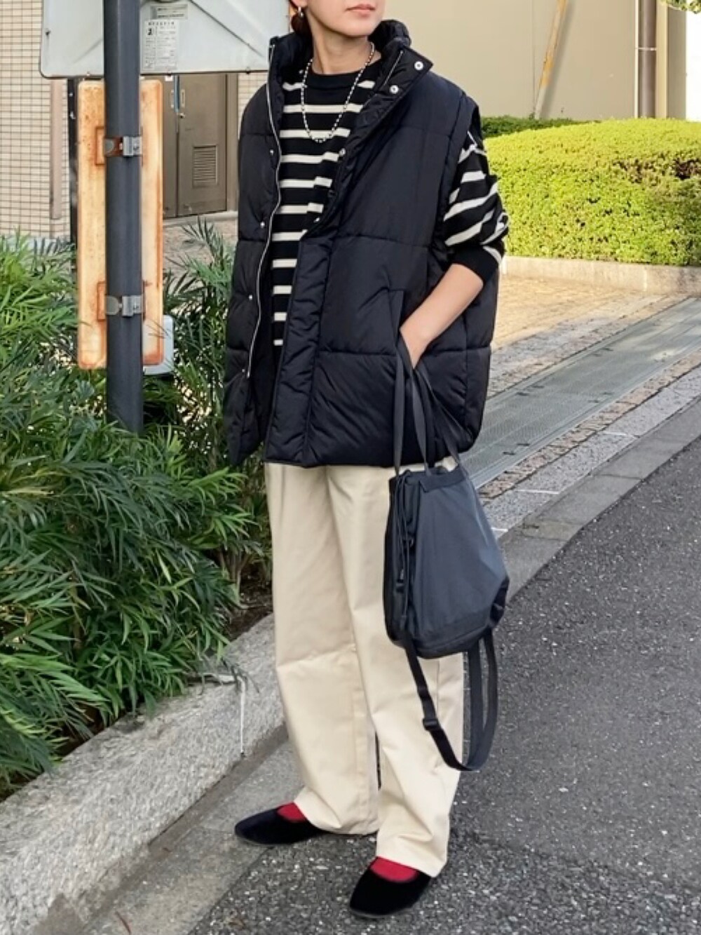 ブラック系のダウンベスト、ベージュ系のチノパンツ、ブラック系のニット/セーターを着用したレディースの秋コーディネートの4枚目の写真