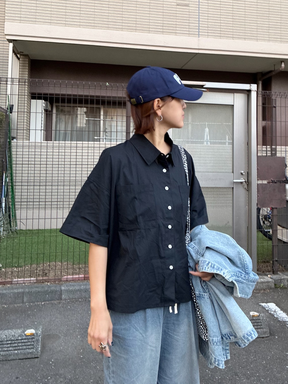ブラック系のシャツ/ブラウス、ブルー系のデニムパンツ、ブルー系のキャップを着用したレディースの春コーディネートの3枚目の写真