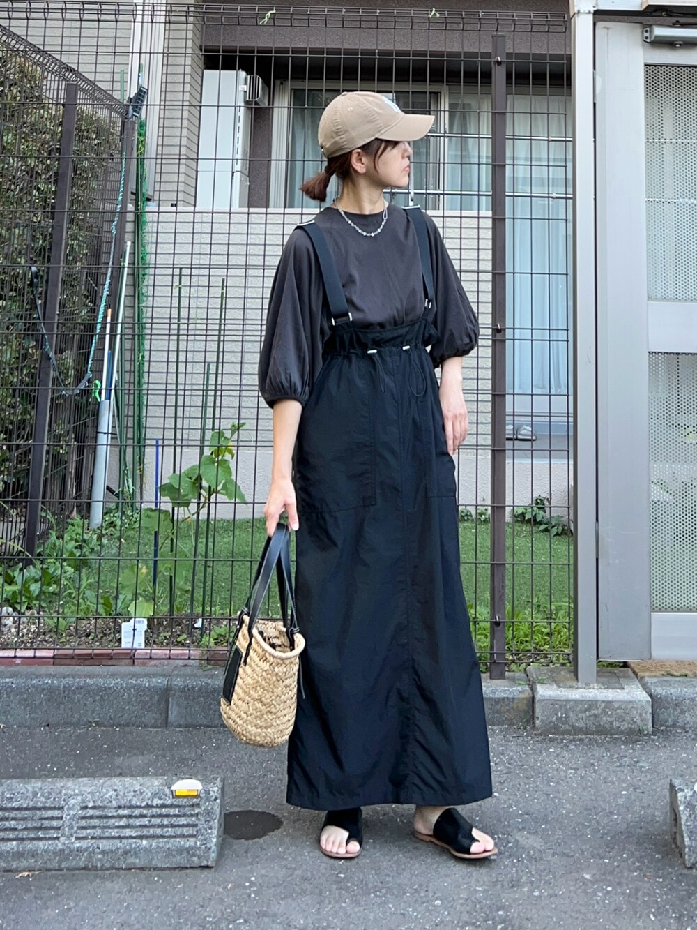 ブラック系のTシャツ/カットソー、ブラック系のジャンパースカート、ブラック系のかごバッグを着用したレディースの夏コーディネートの2枚目の写真
