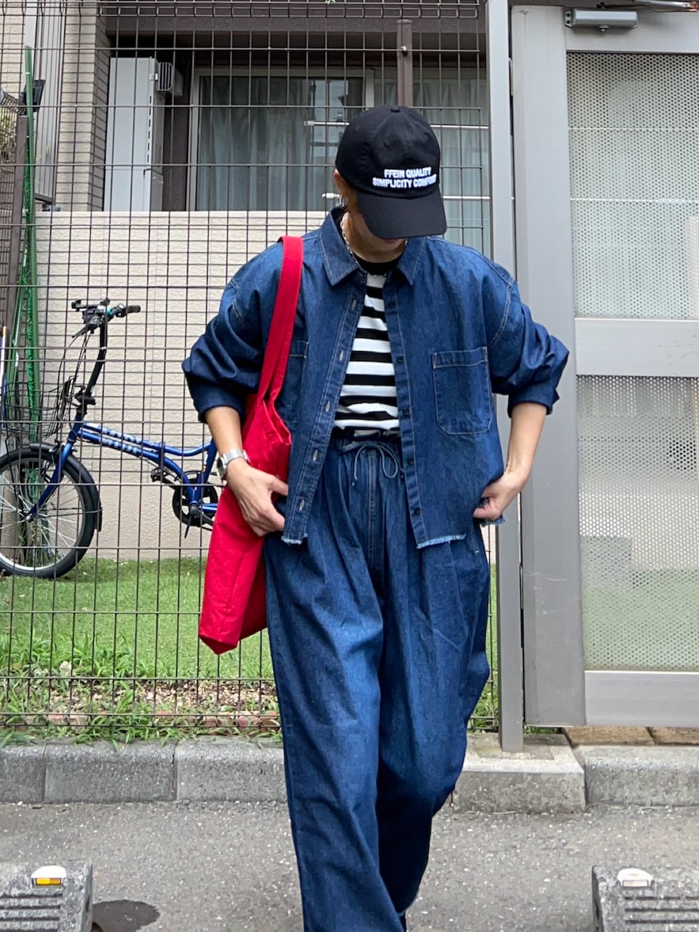 レッド系のトートバッグ、ブルー系のシャツ/ブラウス、ブルー系のデニムパンツを着用したレディースの夏コーディネートの4枚目の写真