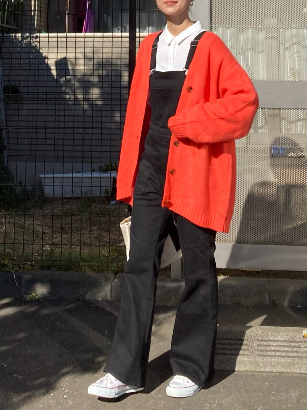 オレンジ系のカーディガン/ボレロ、ホワイト系のシャツ/ブラウス、ブラック系のサロペット/オーバーオールを着用したレディースの冬コーディネートの4枚目の写真