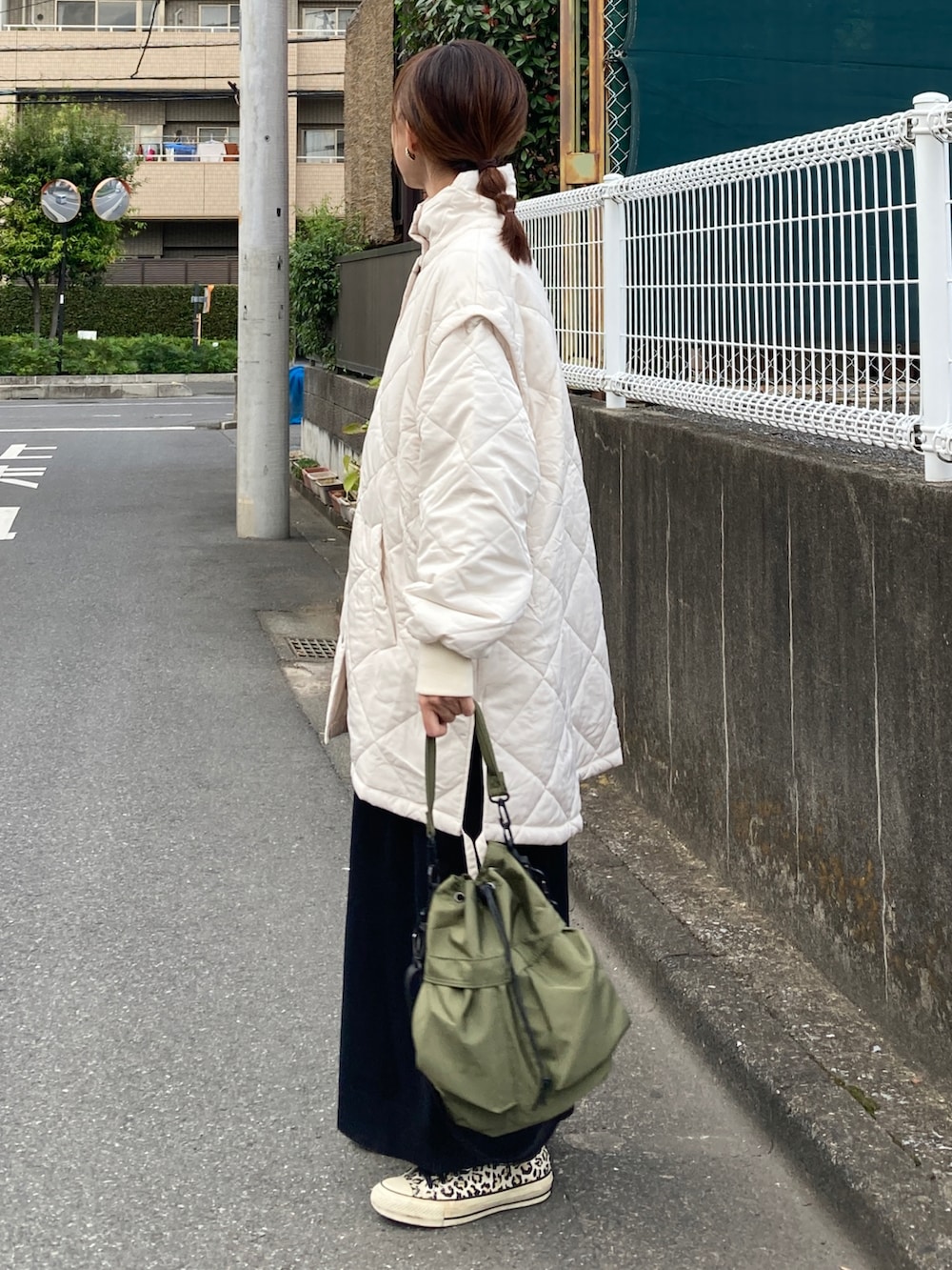 ホワイト系のブルゾン、ブラック系のワンピース、グリーン系のショルダーバッグを着用したレディースの秋コーディネートの4枚目の写真