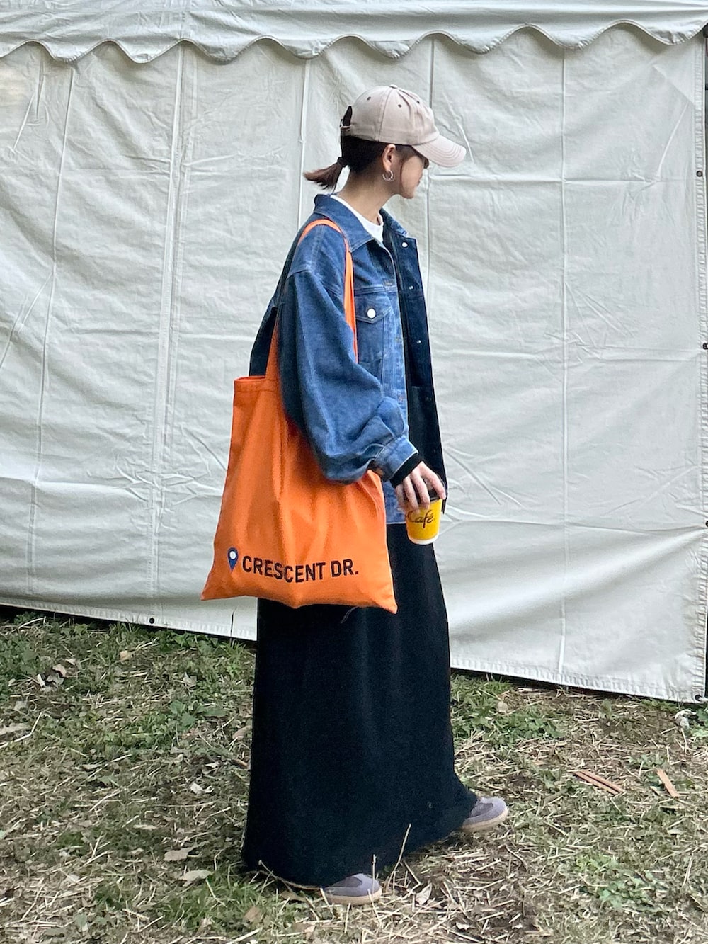 ブラック系のワンピース、ブルー系のデニムジャケット、オレンジ系のトートバッグを着用したレディースの冬コーディネートの2枚目の写真