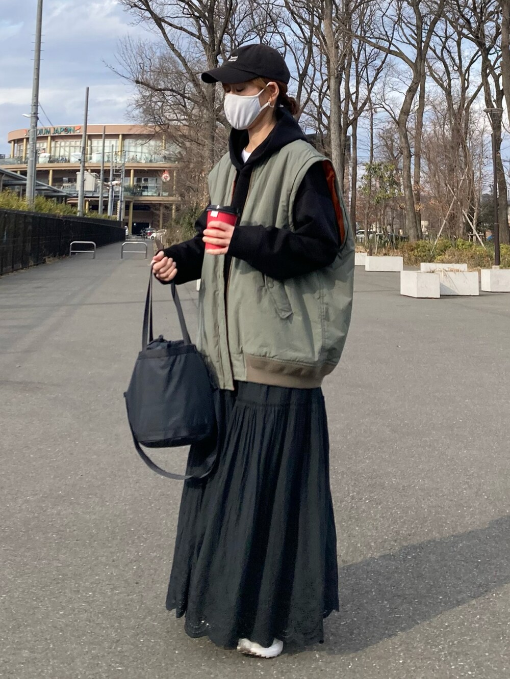 グリーン系のMA-1、ブラック系のパーカー、ブラック系のスカートを着用したレディースの春コーディネートの3枚目の写真