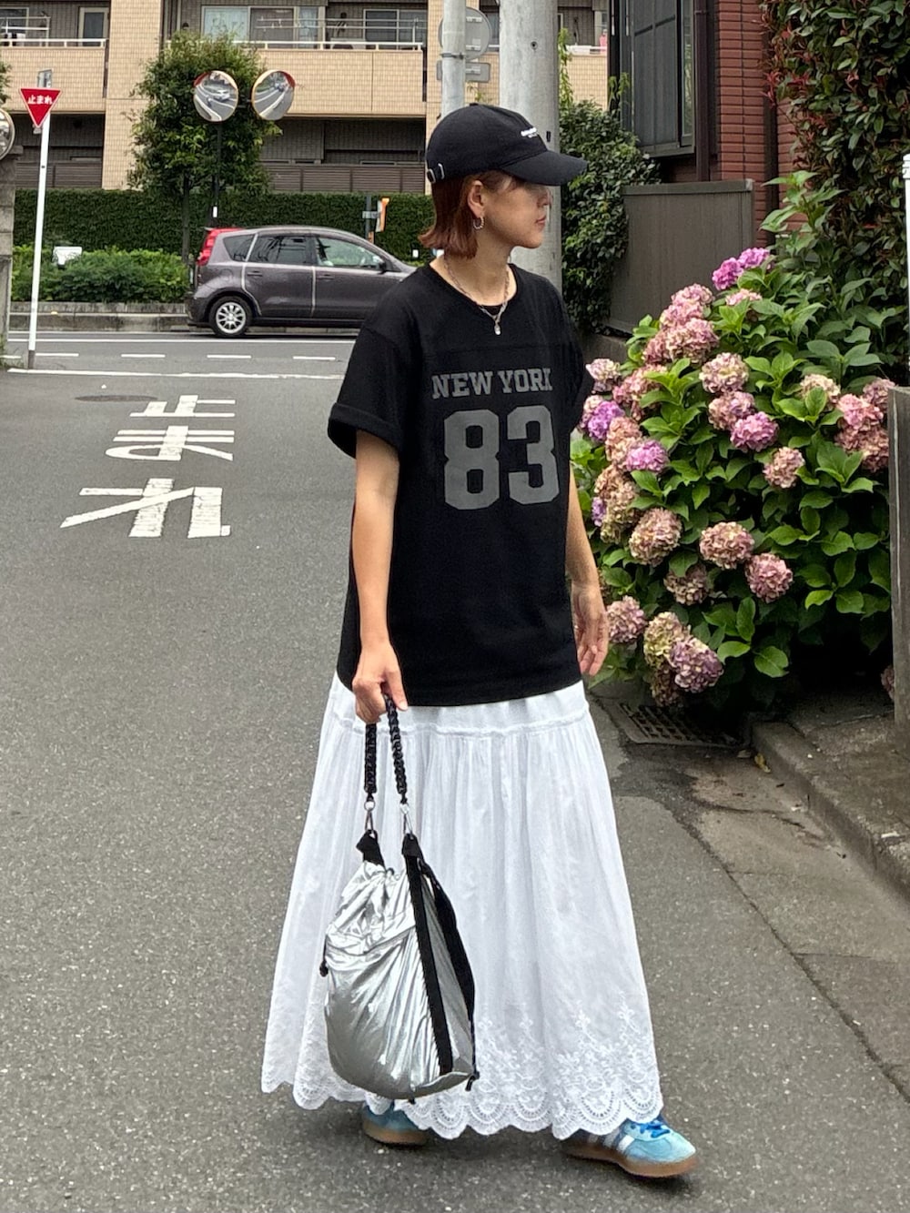 ブラック系のTシャツ/カットソー、ホワイト系のスカート、シルバー系のショルダーバッグを着用したレディースの夏コーディネートの2枚目の写真