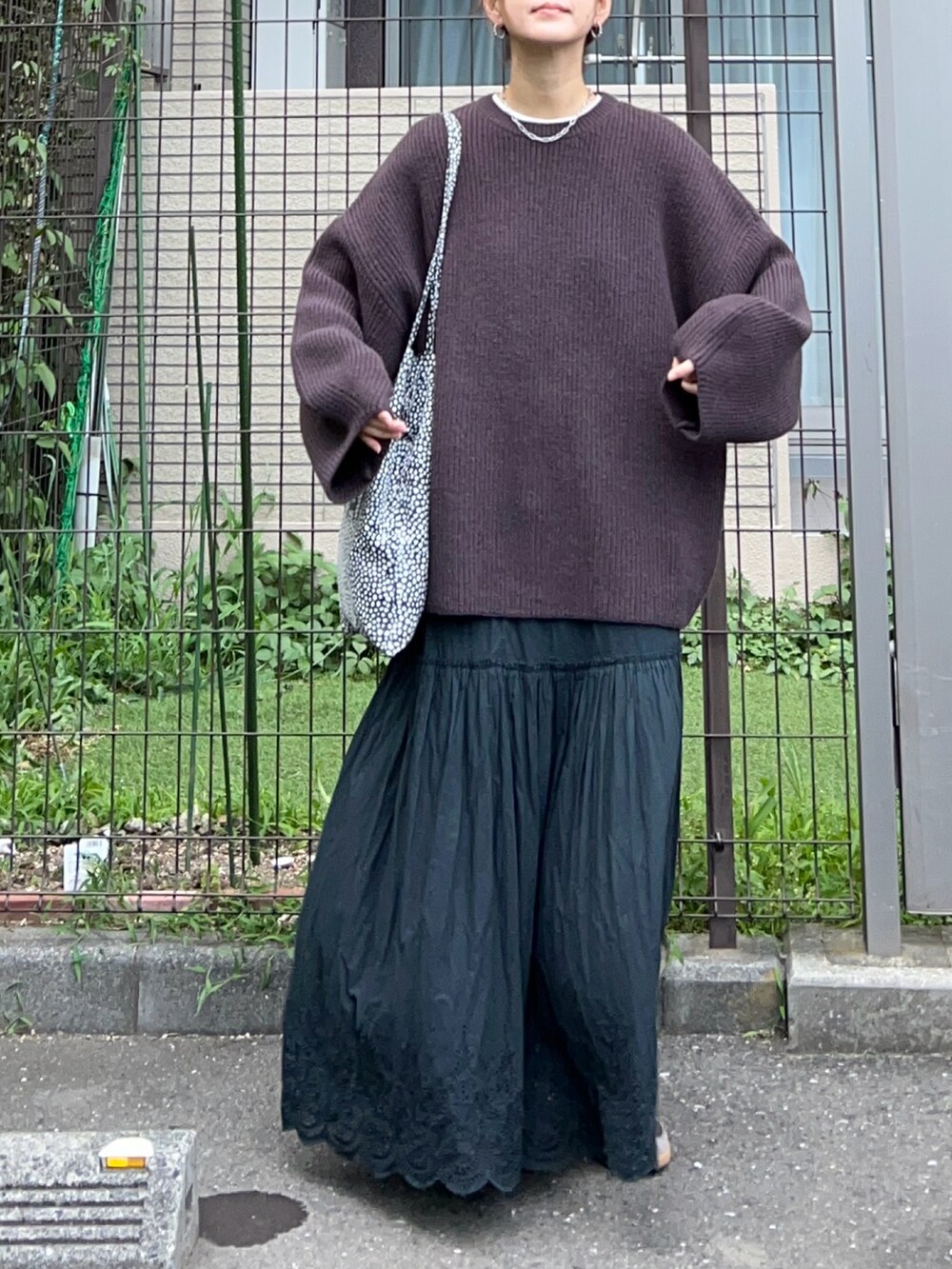 ブラウン系のニット/セーター、ブラック系のスカート、ブラウン系のスニーカーを着用したレディースの夏コーディネートの3枚目の写真