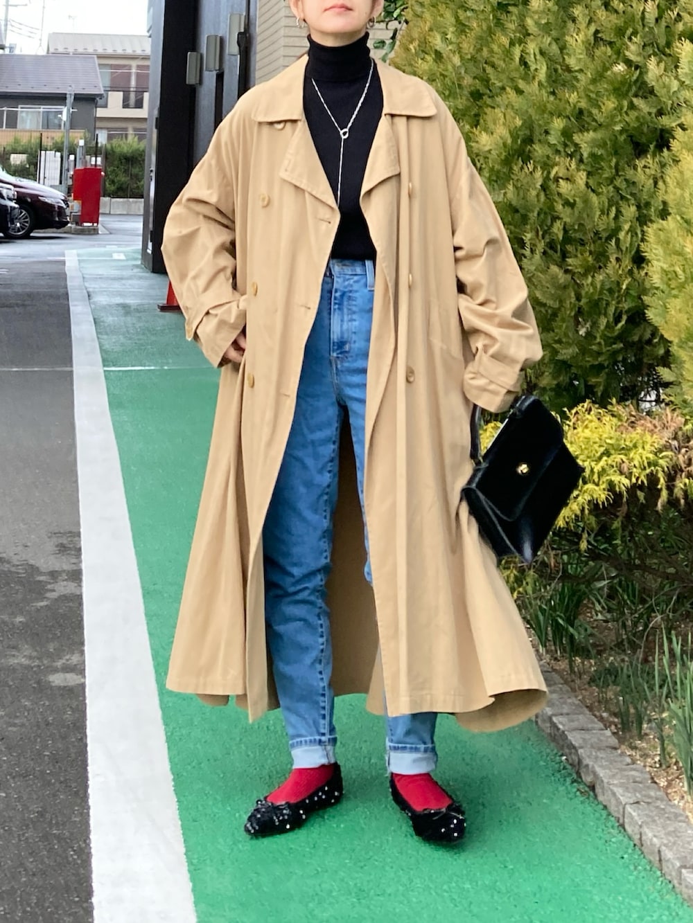 ブラック系のニット/セーター、ブルー系のデニムパンツ、ベージュ系のチェスターコートを着用したレディースの冬コーディネートの4枚目の写真