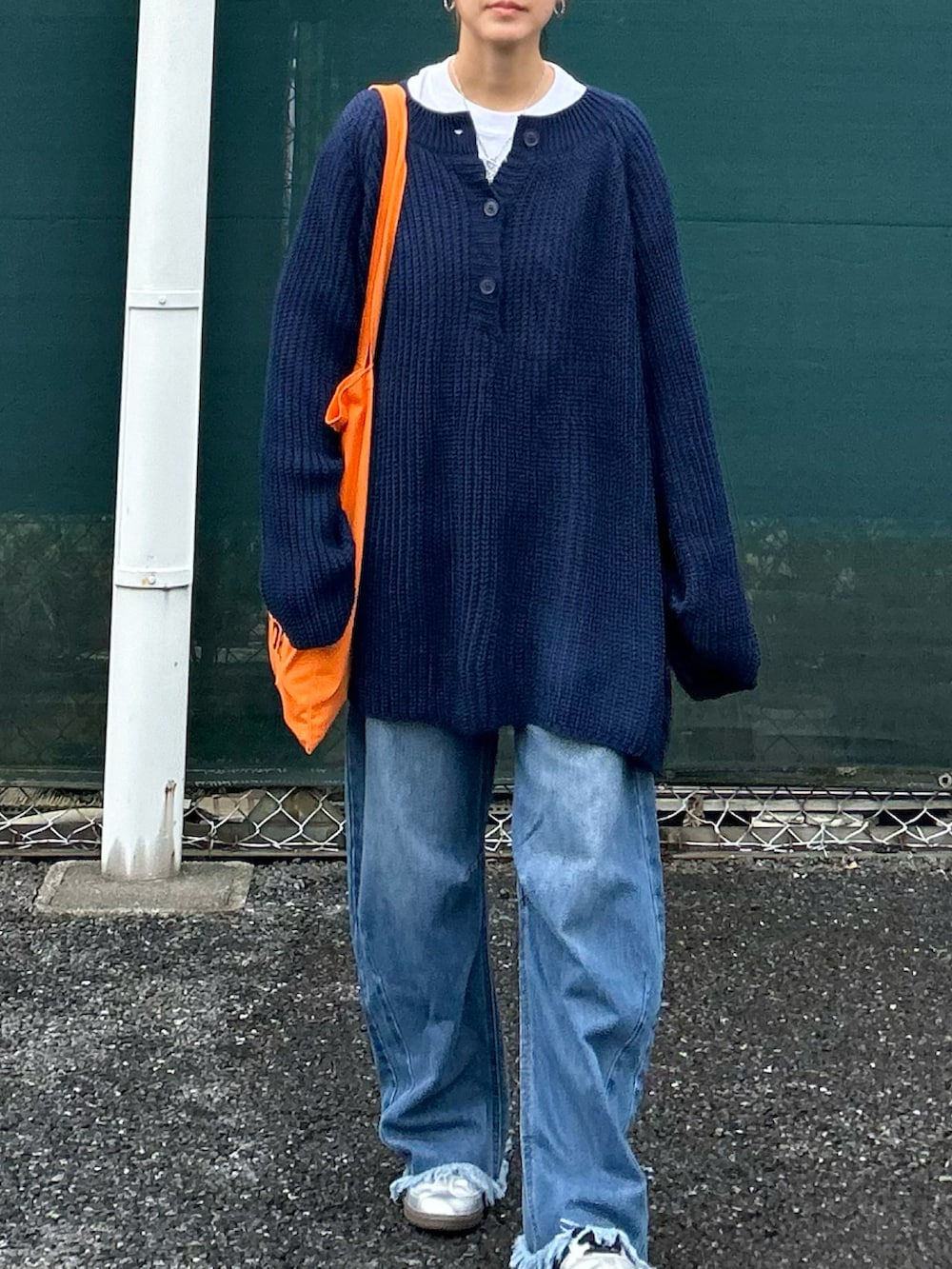 ブルー系のニット/セーター、オレンジ系のトートバッグ、ブルー系のデニムパンツを着用したレディースの秋コーディネートの4枚目の写真