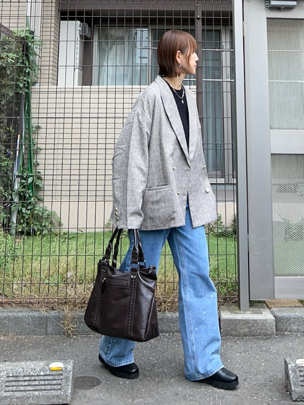 ベージュ系のテーラードジャケット、ブラウン系のトートバッグ、ブラック系のニット/セーターを着用したレディースの秋コーディネートの2枚目の写真