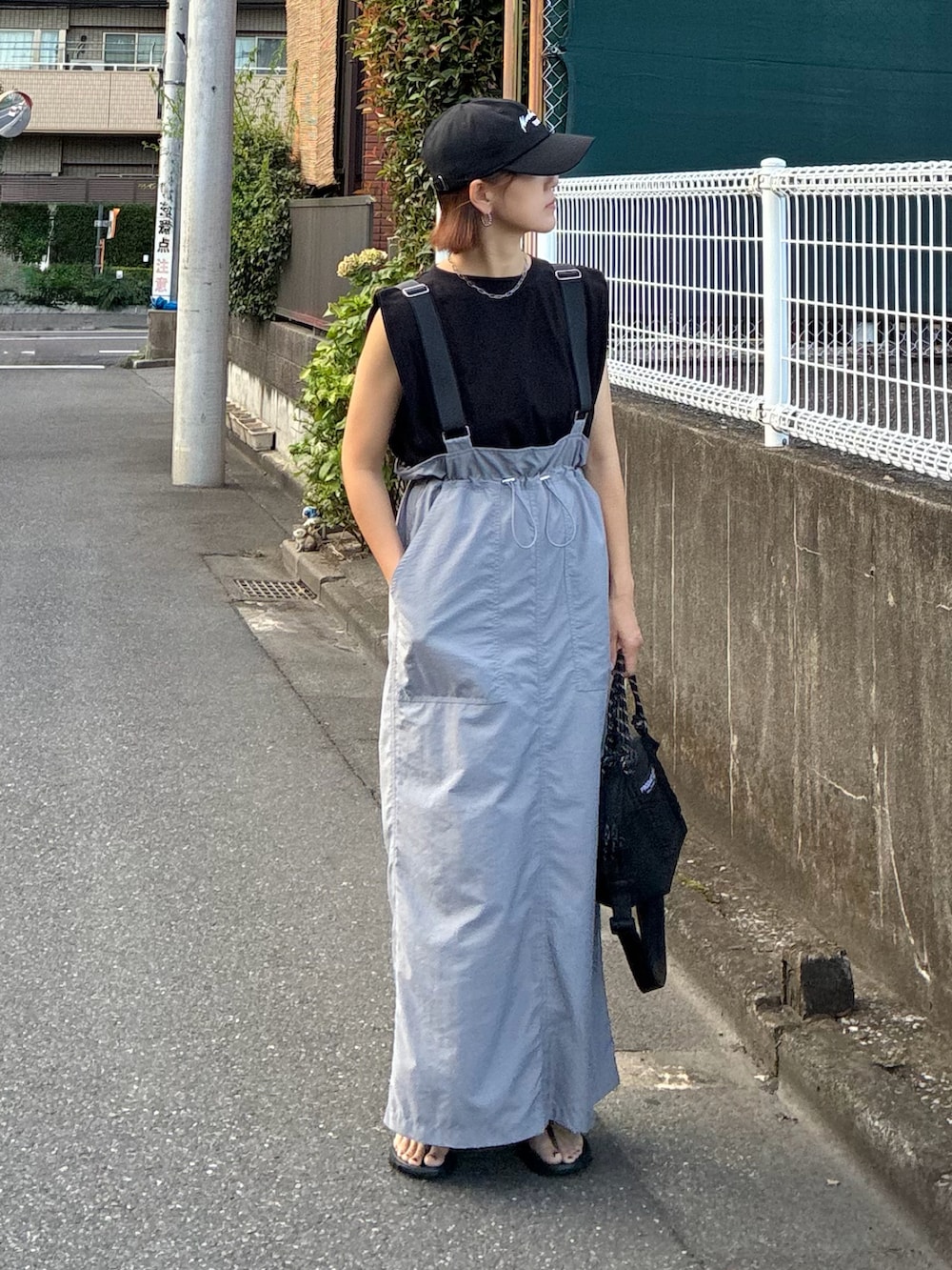 グレー系のジャンパースカート、ブラック系のサンダル、ブラック系のTシャツ/カットソーを着用したレディースの秋コーディネートの3枚目の写真