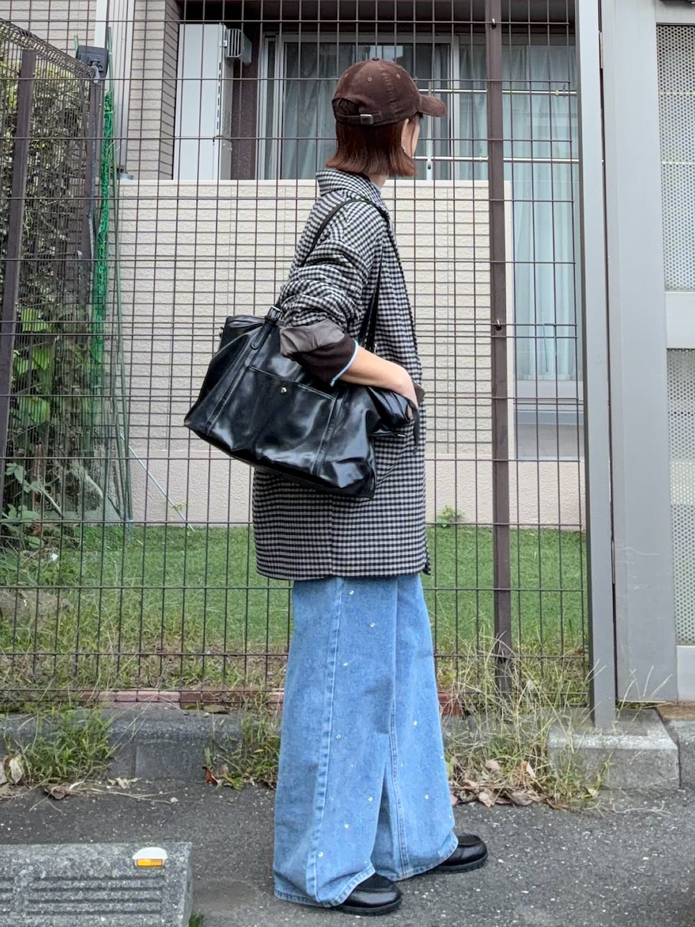 ブラウン系のニット/セーター、ブラック系のトートバッグ、ブルー系のデニムパンツを着用したレディースの秋コーディネートの2枚目の写真