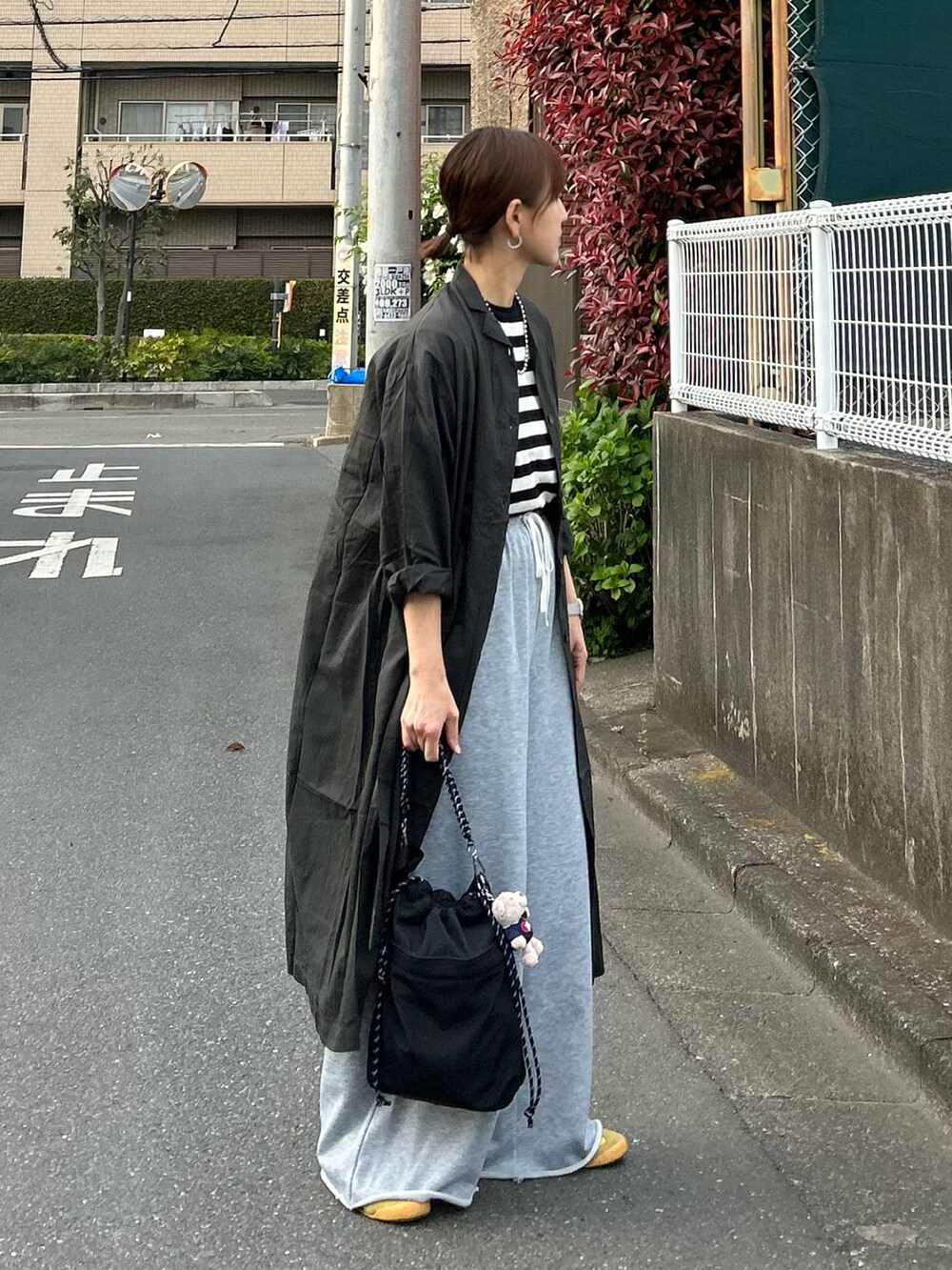 グレー系のワンピース、ブラック系のTシャツ/カットソー、ブラック系のショルダーバッグを着用したレディースの春コーディネートの2枚目の写真