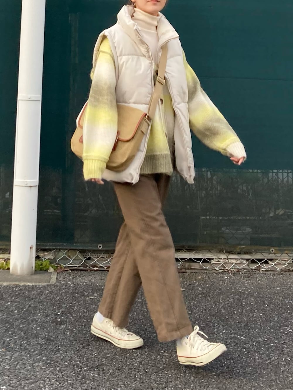 イエロー系のカーディガン/ボレロ、ブラウン系のサロペット/オーバーオール、ベージュ系のショルダーバッグを着用したレディースの冬コーディネートの5枚目の写真